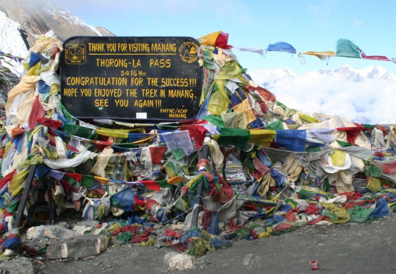 Prayer Flags and Sign on Summit of Tharong La high pass on Annapurna circuit trek in the Nepal Himalaya