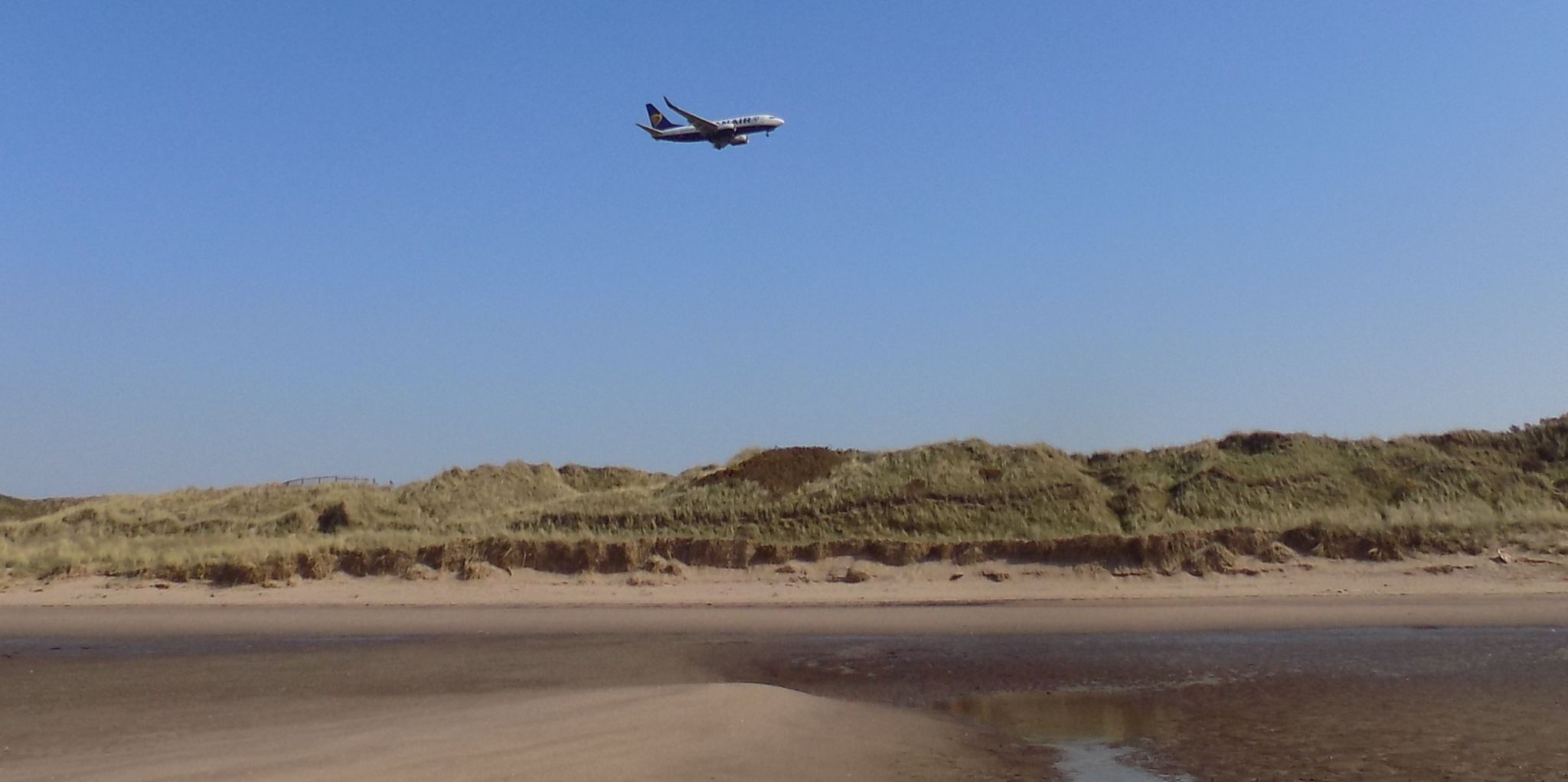 Plane landing at Prestwick Airport above sand dunes and beach