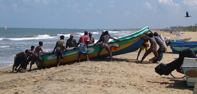 Fishermen hauling boat onto beach at Negombo