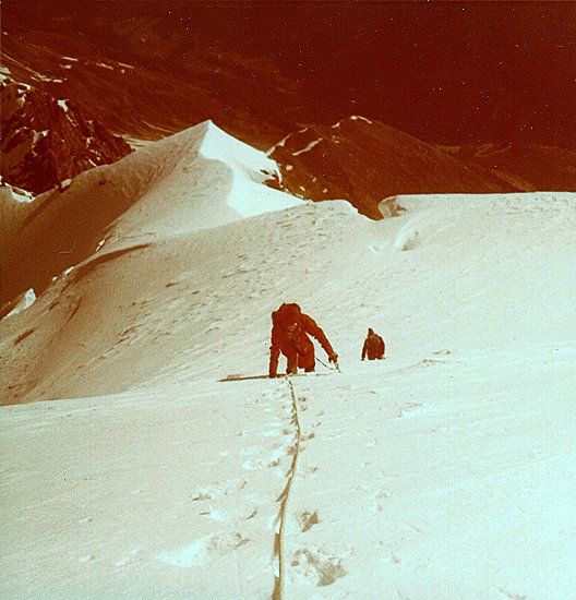 Climbing steep snow slopes to summit